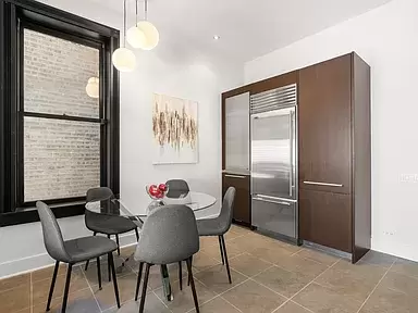 Chicago townhouse's staged kitchen dining with 5 ft glass round dining table and contemporary chairs. Built-in pantry and refrigerator in view.