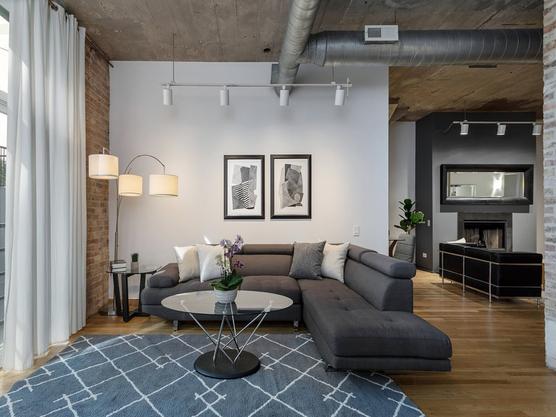 Timber Loft Chicago condo with contemporary masculine furnishings. Includes an arc lamp, gray sectional, and an art print pair in the living room and family room.